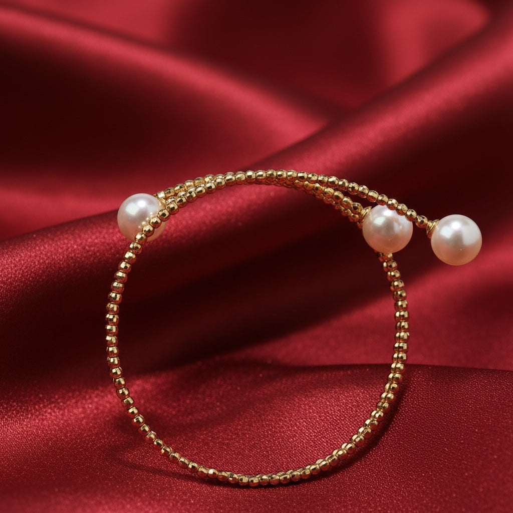 BoxUnboxed 18K yellow gold multi-coil spiral bangle with three Akoya pearls. High-polish finish, faceted beads.