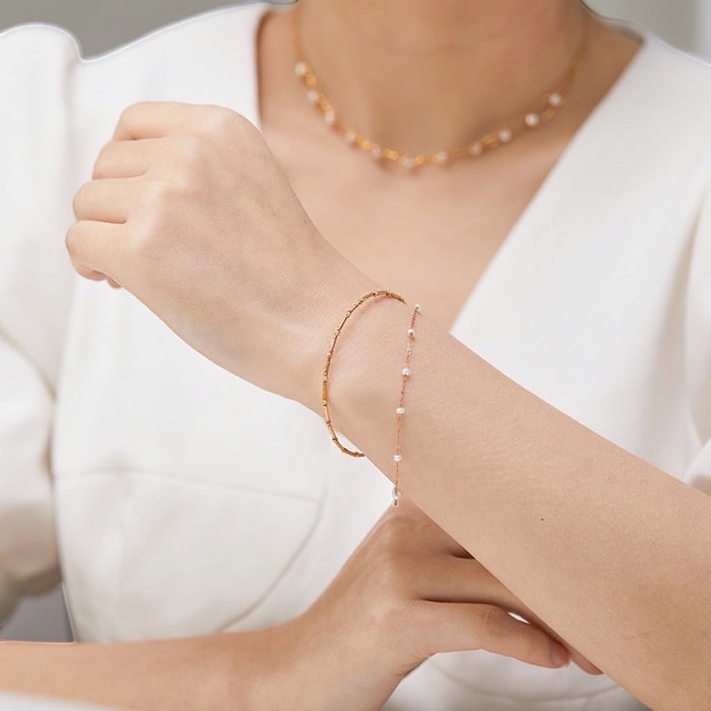 BoxUnboxed Artisanal Signature dual-layer bracelet in 18K gold with delicate pearls and a textured bar chain.