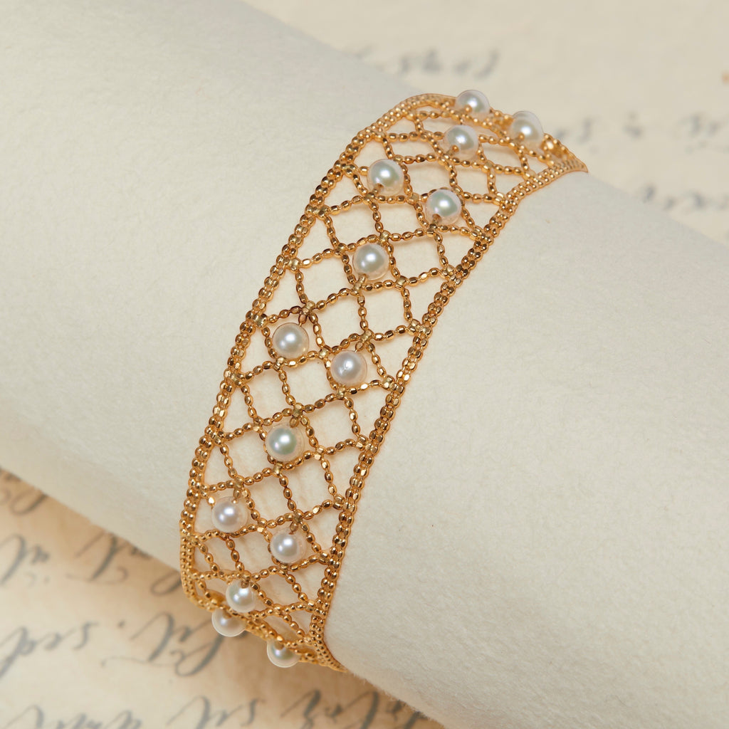 BoxUnboxed 18k yellow gold lace lattice bracelet with Akoya pearls. Features a flexible, woven gold design with small, round pearls.