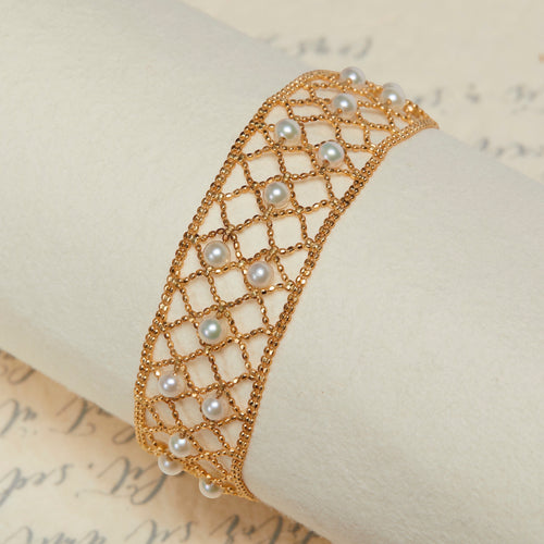 BoxUnboxed 18k yellow gold lace lattice bracelet with Akoya pearls. Features a flexible, woven gold design with small, round pearls.