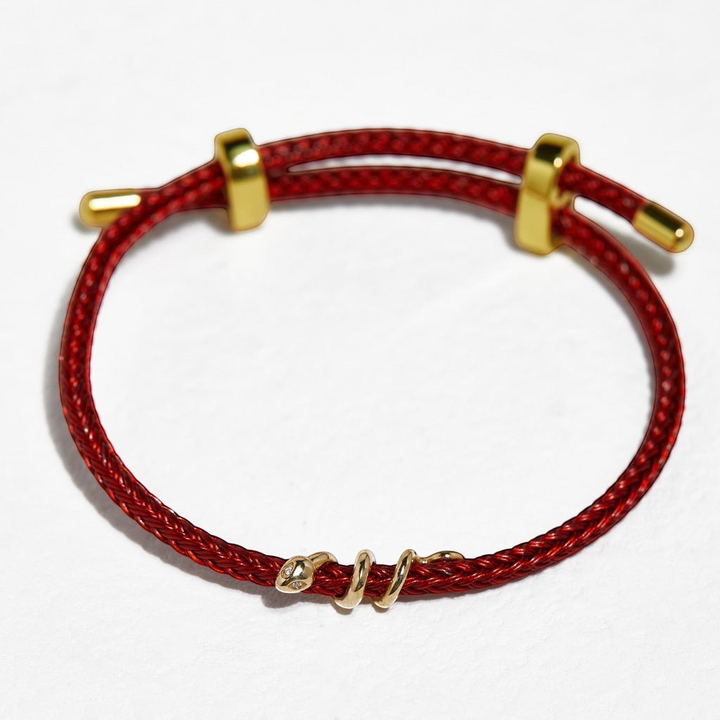 BoxUnboxed 18k solid gold snake bracelet with diamond eyes on red string cord. Adjustable fit.