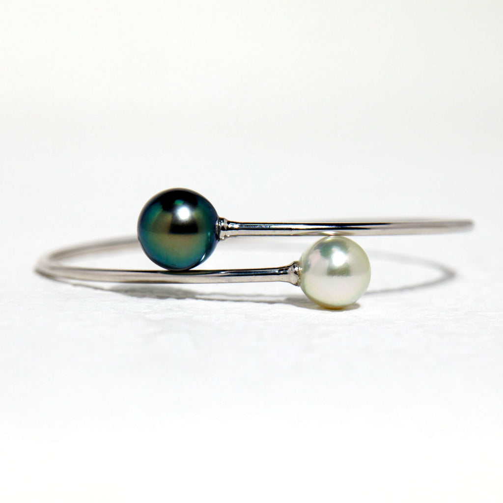 BoxUnboxed 18K white gold bypass bangle with a dark peacock Tahitian pearl and a white Akoya pearl.